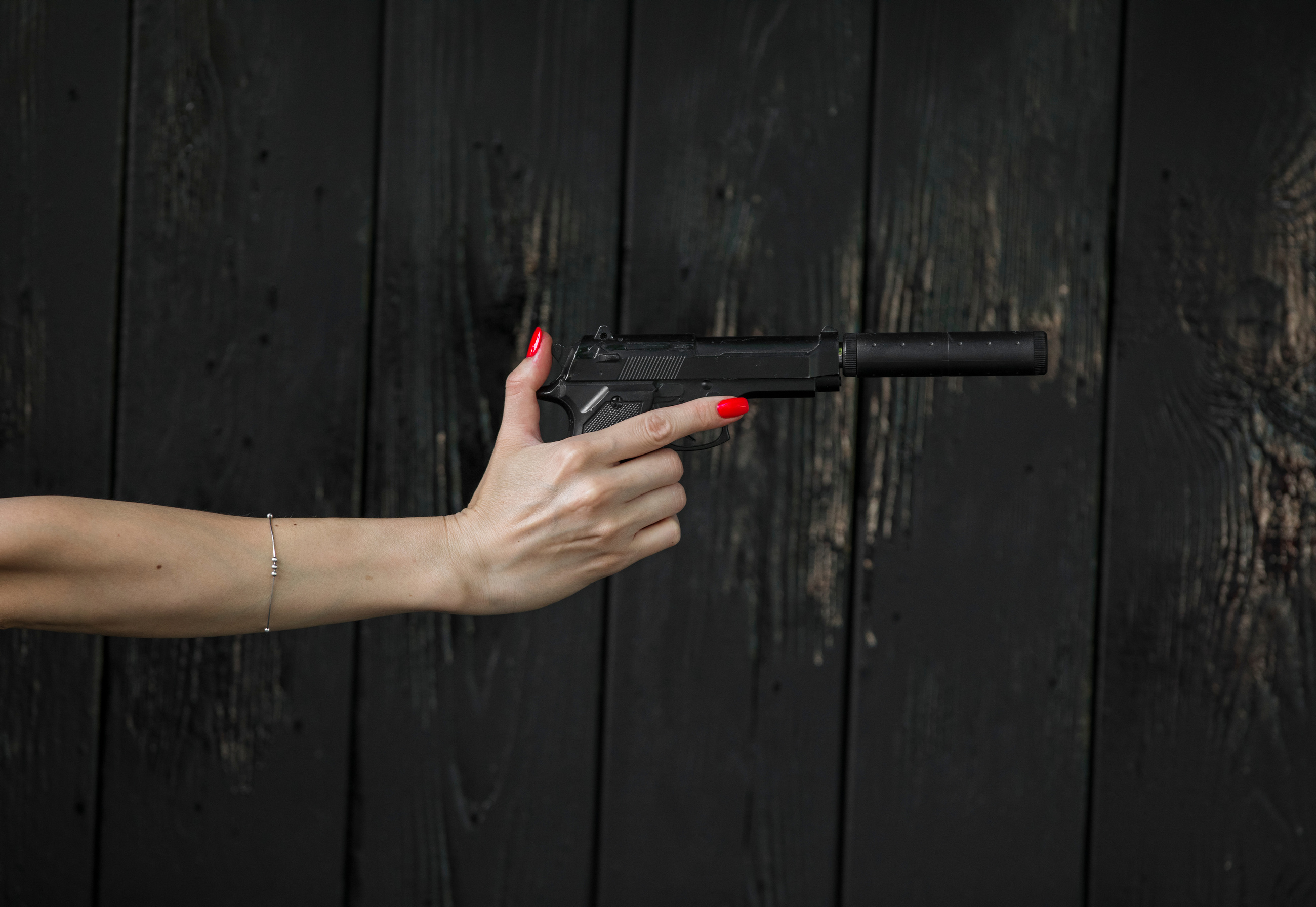 woman's hand with a pistol with a silencer